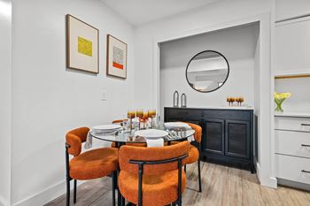 A dining room with a round table and orange chairs.